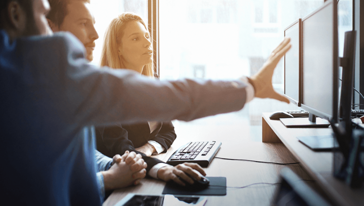 Deux hommes et deux femmes travaillant dans un environnement de bureau, utilisant la technologie.